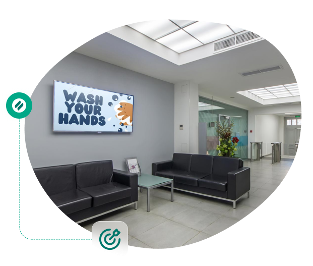 A modern lobby with a digital screen displaying a Wash Your Hands message, connected to icons symbolizing digital signage and remote content management.