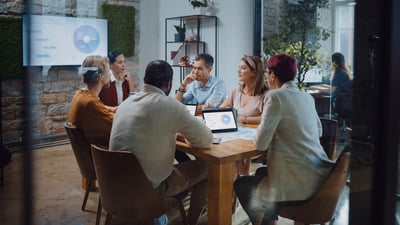 People sharing a device screen wirelessly to a TV during a meeting