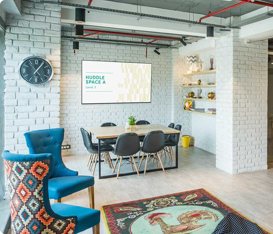 Huddle space with a desk, chairs and a TV running digital signage