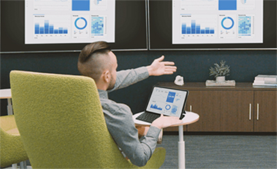 Man screen mirroring a computer to two TVs during a meeting