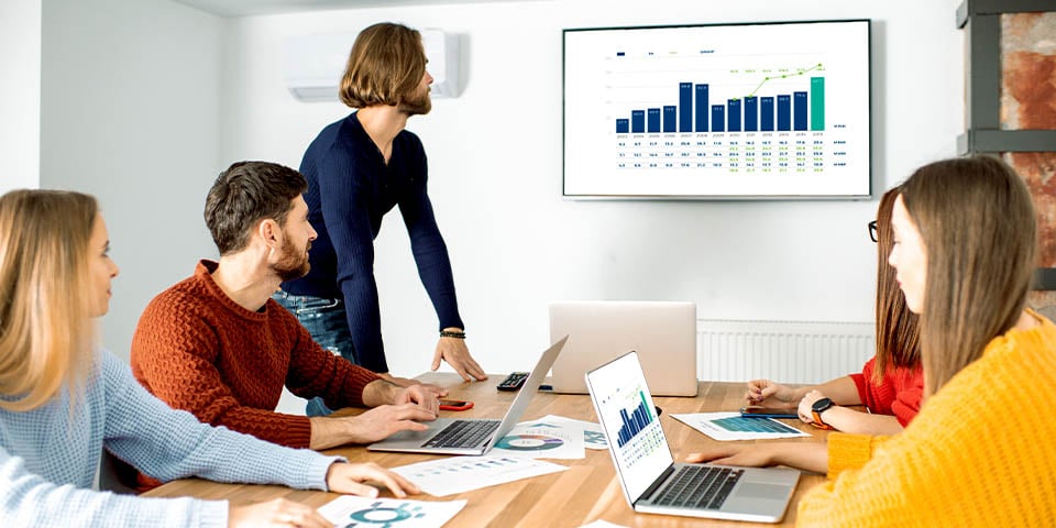 People in a conference room screen mirroring a computer to a TV