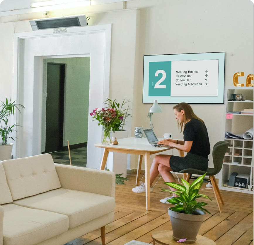 Person sitting at a table with digital signage on a screen in the background